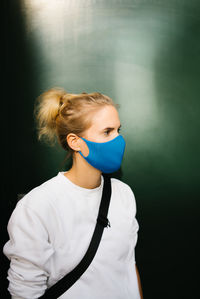 Portrait of young woman standing against black background