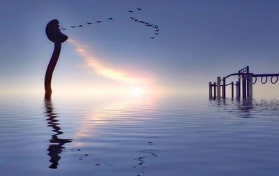 Silhouette bird flying over sea against sky during sunset