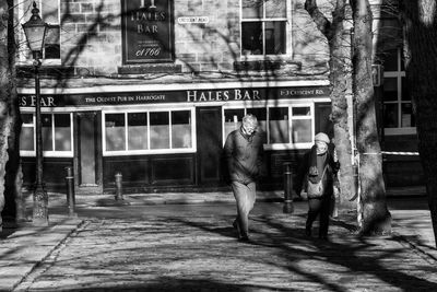 Rear view of man walking on street against building