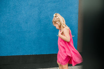 Portrait of young woman standing against blue wall