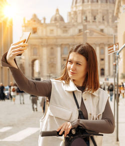 Beautiful young woman takes a selfie on a smartphone while walking in rome  tourist travel concept. 