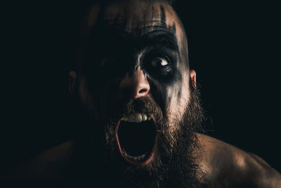 Portrait of a viking warrior with black war paint, screaming with rage and anger