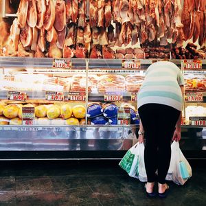 Rear view of woman bending against store