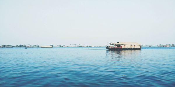 Boat sailing in sea against clear sky