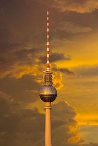 Fernsehturm against cloudy sky during sunset