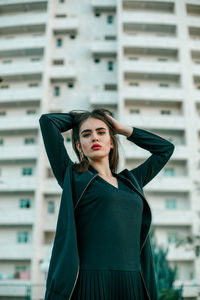 Young woman looking away while standing against brick wall