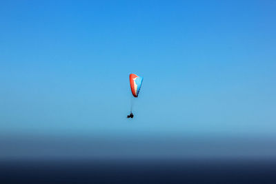 Person paragliding against clear sky