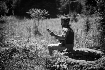 Side view of man using mobile phone in field