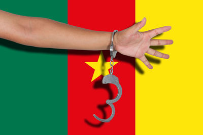 Cropped hand of person wearing handcuffs against flag