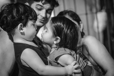 Close-up of sisters kissing while parent looking at them 