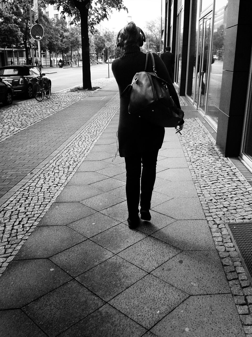full length, lifestyles, street, walking, shadow, rear view, leisure activity, sunlight, sidewalk, footpath, casual clothing, city, person, city life, tree, cobblestone, road, day