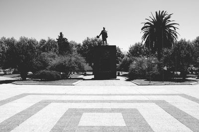 Silhouette sculpture in city against clear sky