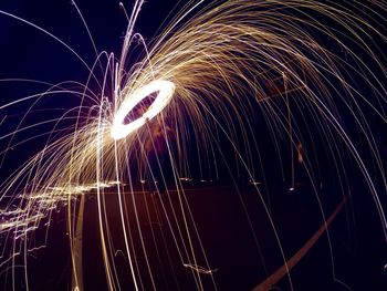 Man spinning illuminated wire wool at night