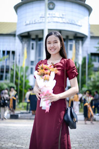 Portrait of smiling young woman standing in city