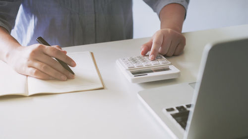 Midsection of woman using mobile phone on table