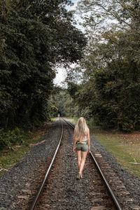 Rear view of man walking on railroad track