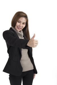 Portrait of smiling young woman standing against white background