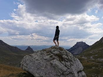 Full length of man standing on rock against sky