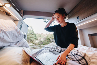 Side view of young woman reading book at home