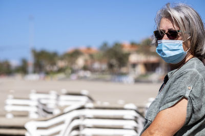 Portrait of smiling senior woman wearing mask while standing outdoors