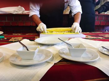 Midsection of chef preparing food at table in restaurant