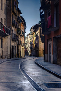 Empty road amidst buildings in city