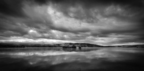 Scenic view of lake and mountains against dramatic sky