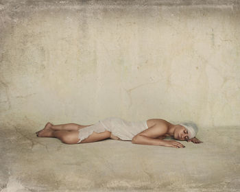 Mature woman sleeping on floor against wall