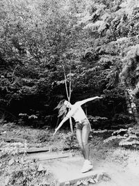Rear view of woman standing by tree in forest