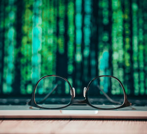 Close-up of eyeglasses on table against trees in forest