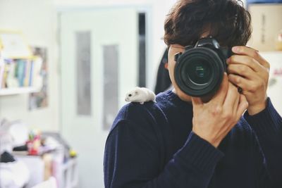 Rat on shoulder of woman photographing through slr camera at home