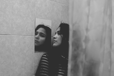 Young woman looking at mirror in bathroom