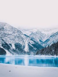 Scenic view of lake by snowcapped mountains against sky