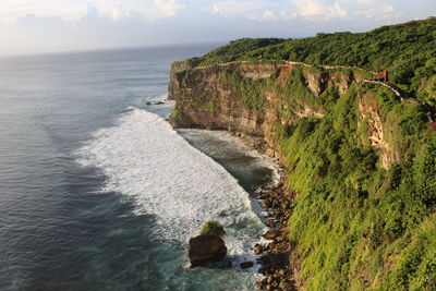 Scenic view of sea by cliff against sky