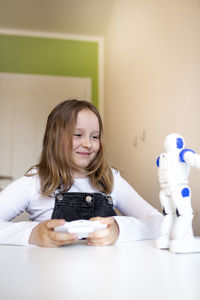 Portrait of smiling girl sitting on table at home