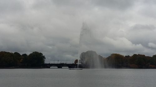 View of fountain in water against cloudy sky