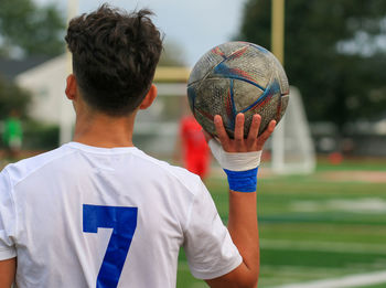 A young boy holding a soccer ball ready too do a throw in during a game.