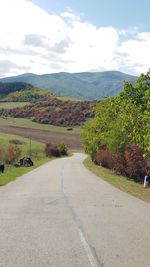 Road leading towards mountains against sky