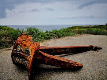 Rusty metal on beach against sky