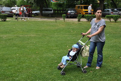 Mother with daughter in baby stroller standing at park