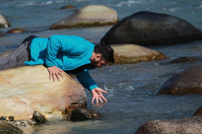 Man lying on rock at river