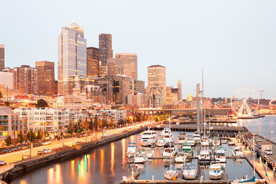 Aerial view of buildings in city by sea against sky