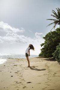 Side view of carefree woman standing on beach