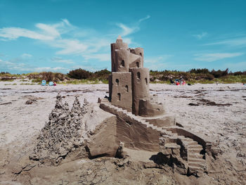 Old ruin on sand at beach against sky