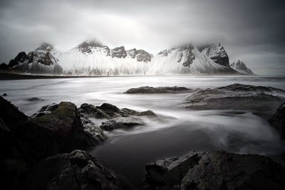 Scenic view of sea by mountains against sky