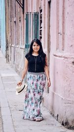 Portrait of young woman standing against wall