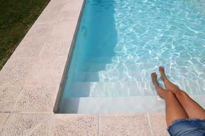 Low section of person relaxing in swimming pool