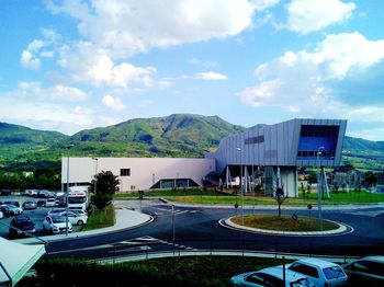 Road by buildings in city against sky