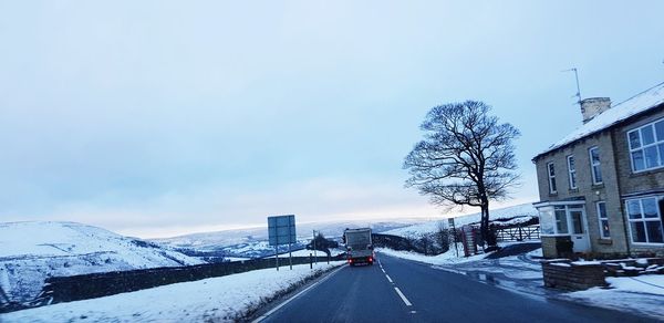 Snow covered road against sky in city