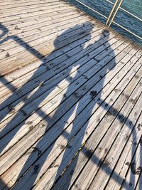 High angle view of shadow on wooden pier